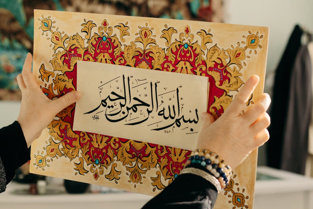 Arabic calligraphy on ornate frame held by hands, highlighting artistic beauty.